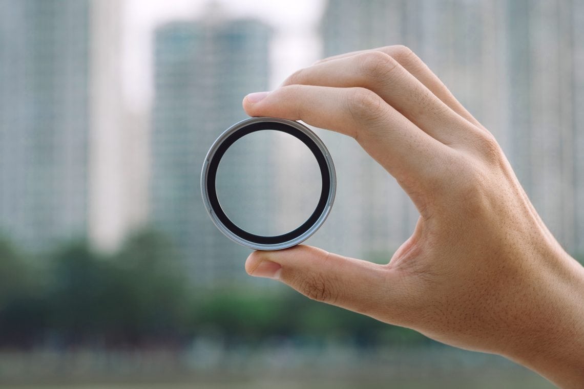 Hand holding the NiSi NC UV 49MAG Adapter up to the light in the city